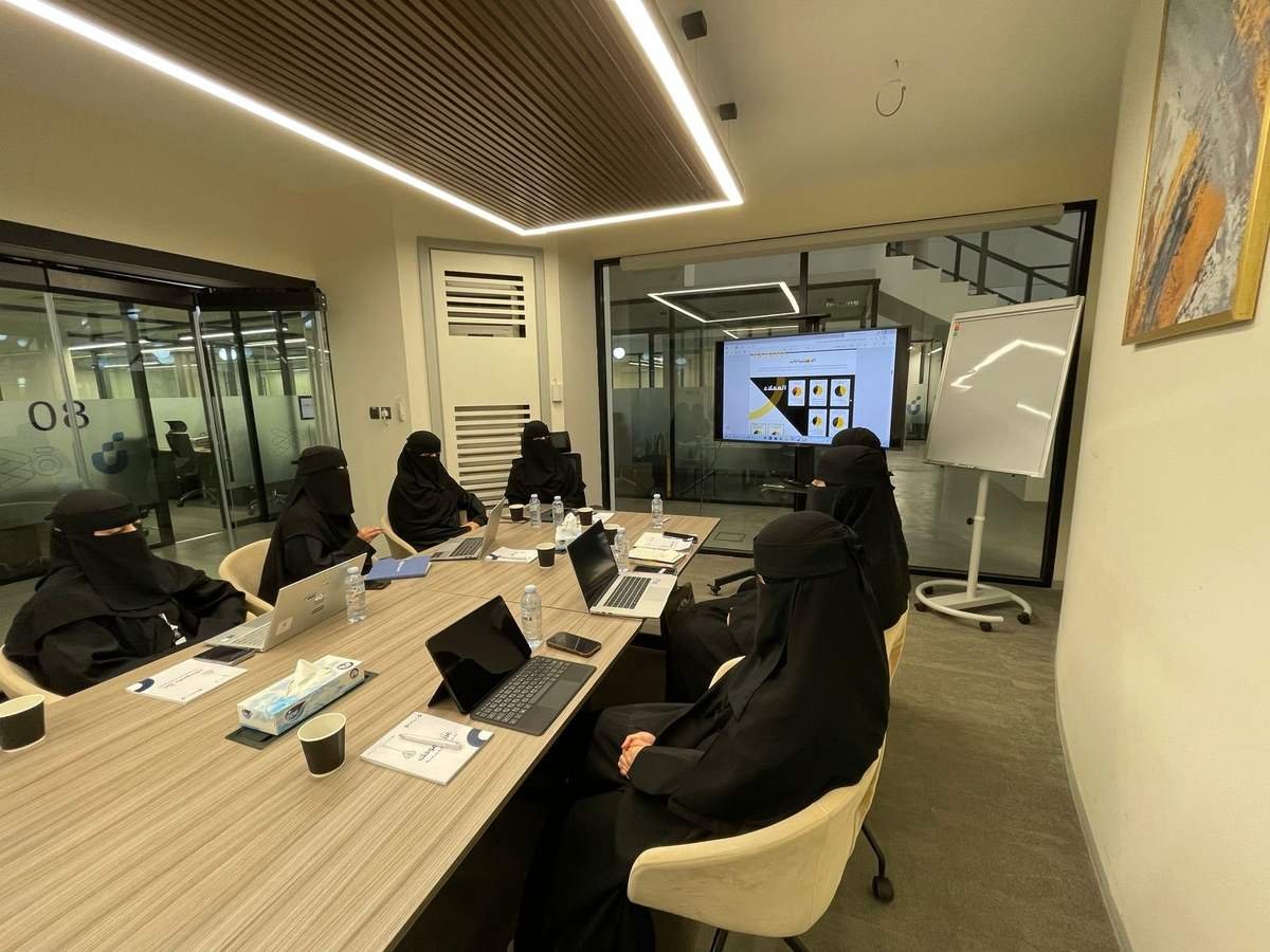 فريق مشارك في تجربة محاكاة داخل قاعة اجتماعات، يتابع عرضًا على الشاشة أمام أجهزة الحاسب.